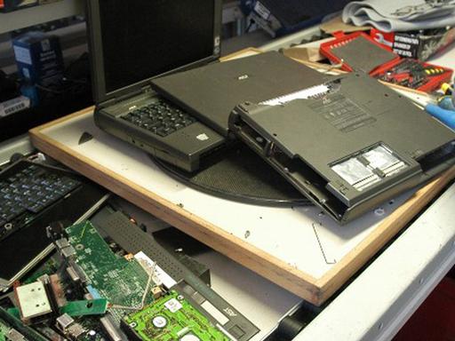 Ein Arbeiter entnimmt einem Laptop Wertstoffe wie Edelmetalle zur Wiederverwertung.