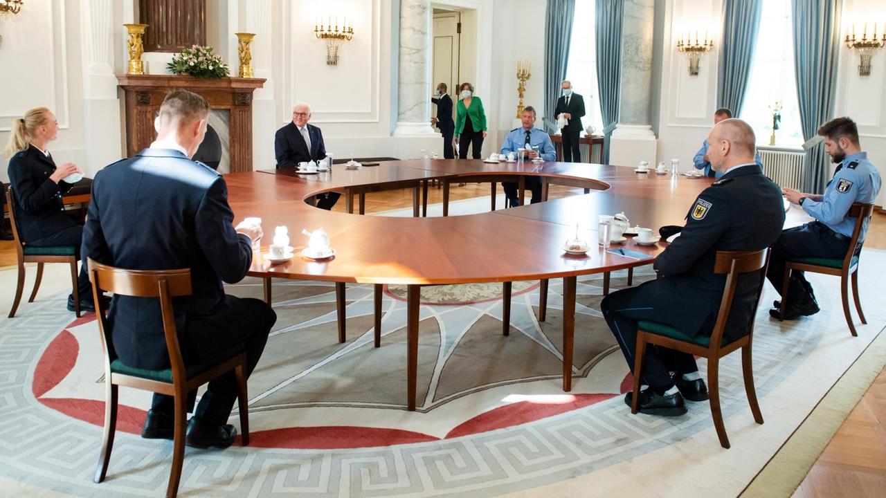 Bundespräsident Frank-Walter Steinmeier und die Polizistinnen und Polizisten sitzen um einen großen, runden Tisch herum. Bundespräsident Frank-Walter Steinmeier und die Polizistinnen und Polizisten sitzen um einen großen, runden Tisch herum.