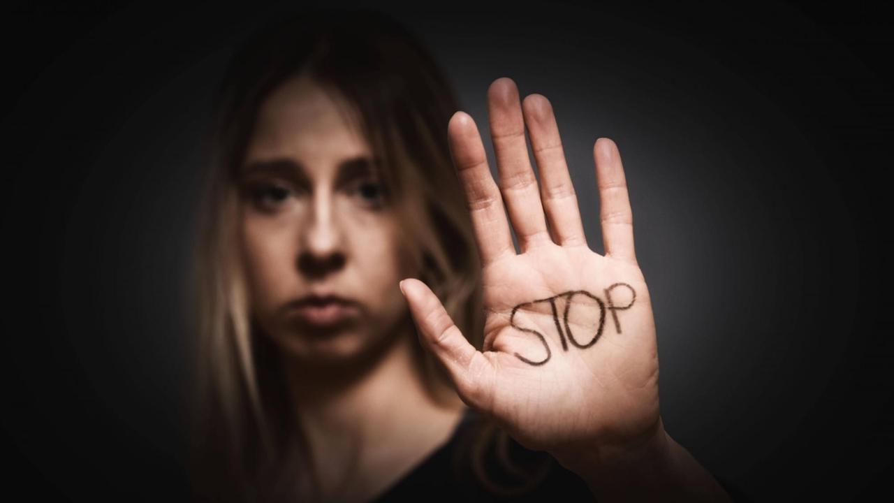 Eine Frau hält ihre Handfläche Richtung Kamera. Darauf steht "Stop".