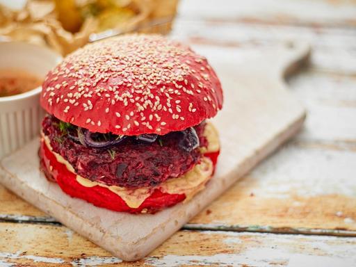 From above vegan beetroot burger placed on cutting board on shabby table of cafe