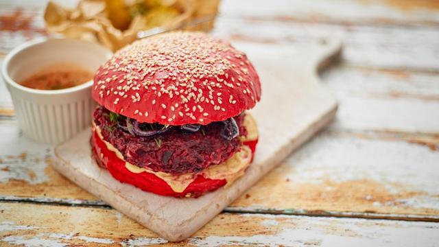 From above vegan beetroot burger placed on cutting board on shabby table of cafe