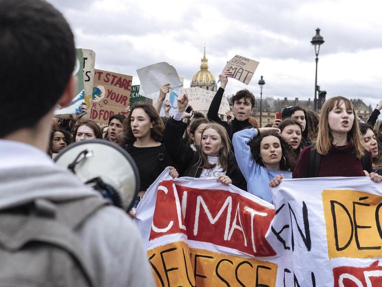 Junge Menschen demonstrieren für eine andere Klimapolitik. Sie halten Transparten vor sich, auf denen Worte auf Franösisch stehen.