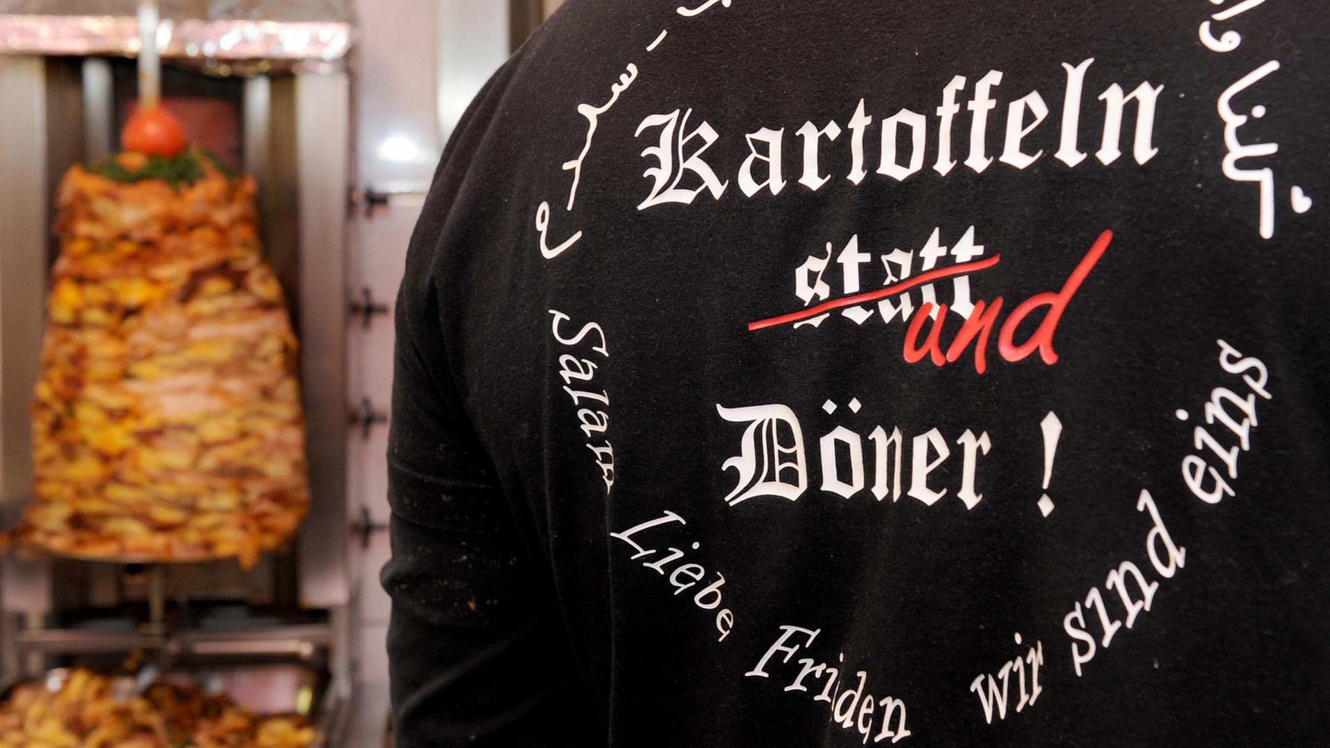 Mann im T-Shirt mit der Aufschrift "Kartoffeln und Döner" vor einem Döner-Spieß Mann im T-Shirt mit der Aufschrift "Kartoffeln und Döner" vor einem Döner-Spieß