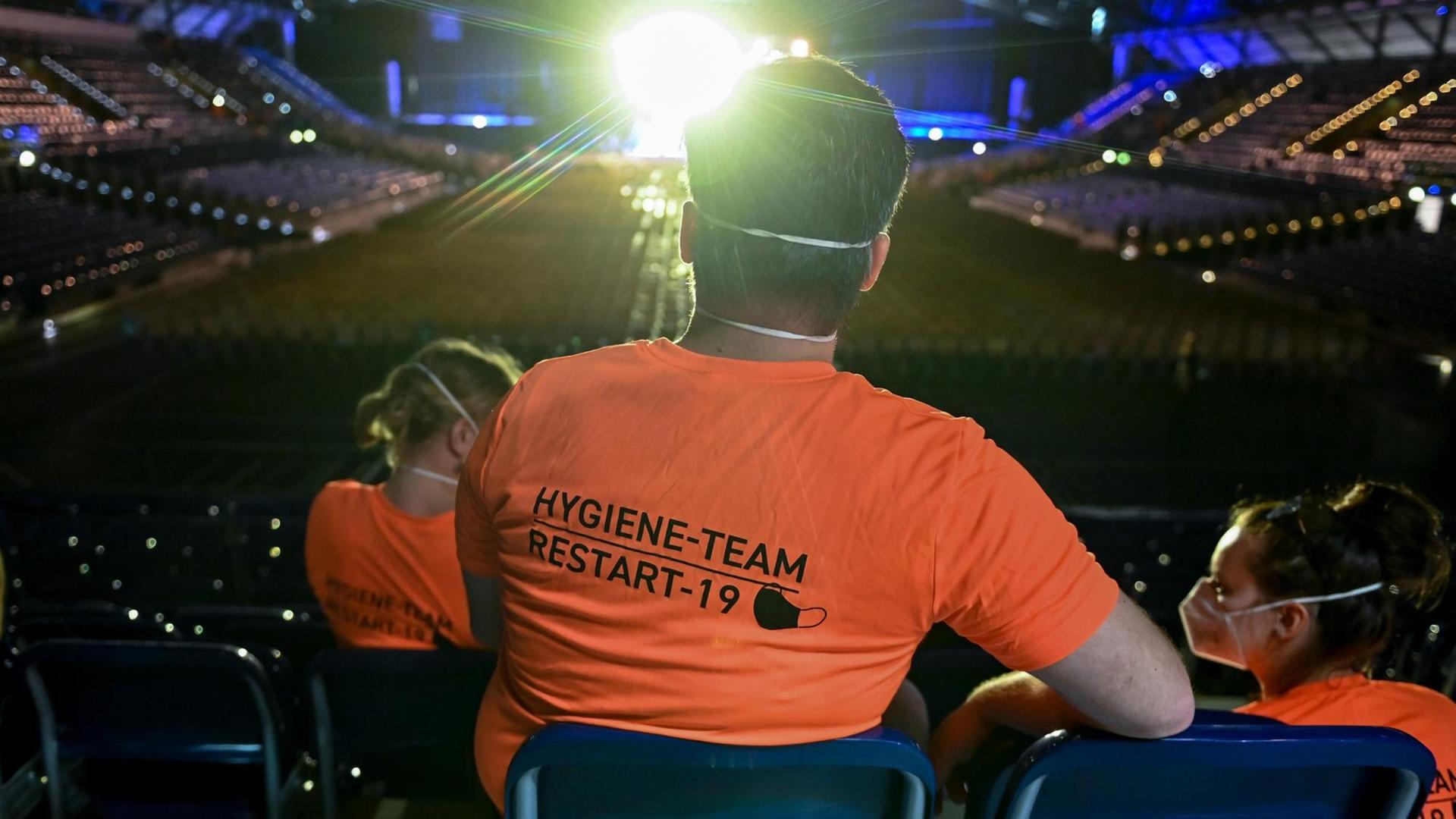 Bei einem Konzert sitzt ein Experiment-Helfer in orangefarbenem T-Shirt in einer der letzten Reihen und Beobachtet das Geschehen. Bei einem Konzert sitzt ein Experiment-Helfer in orangefarbenem T-Shirt in einer der letzten Reihen und Beobachtet das Geschehen.