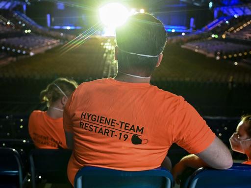 Bei einem Konzert sitzt ein Experiment-Helfer in orangefarbenem T-Shirt in einer der letzten Reihen und Beobachtet das Geschehen.