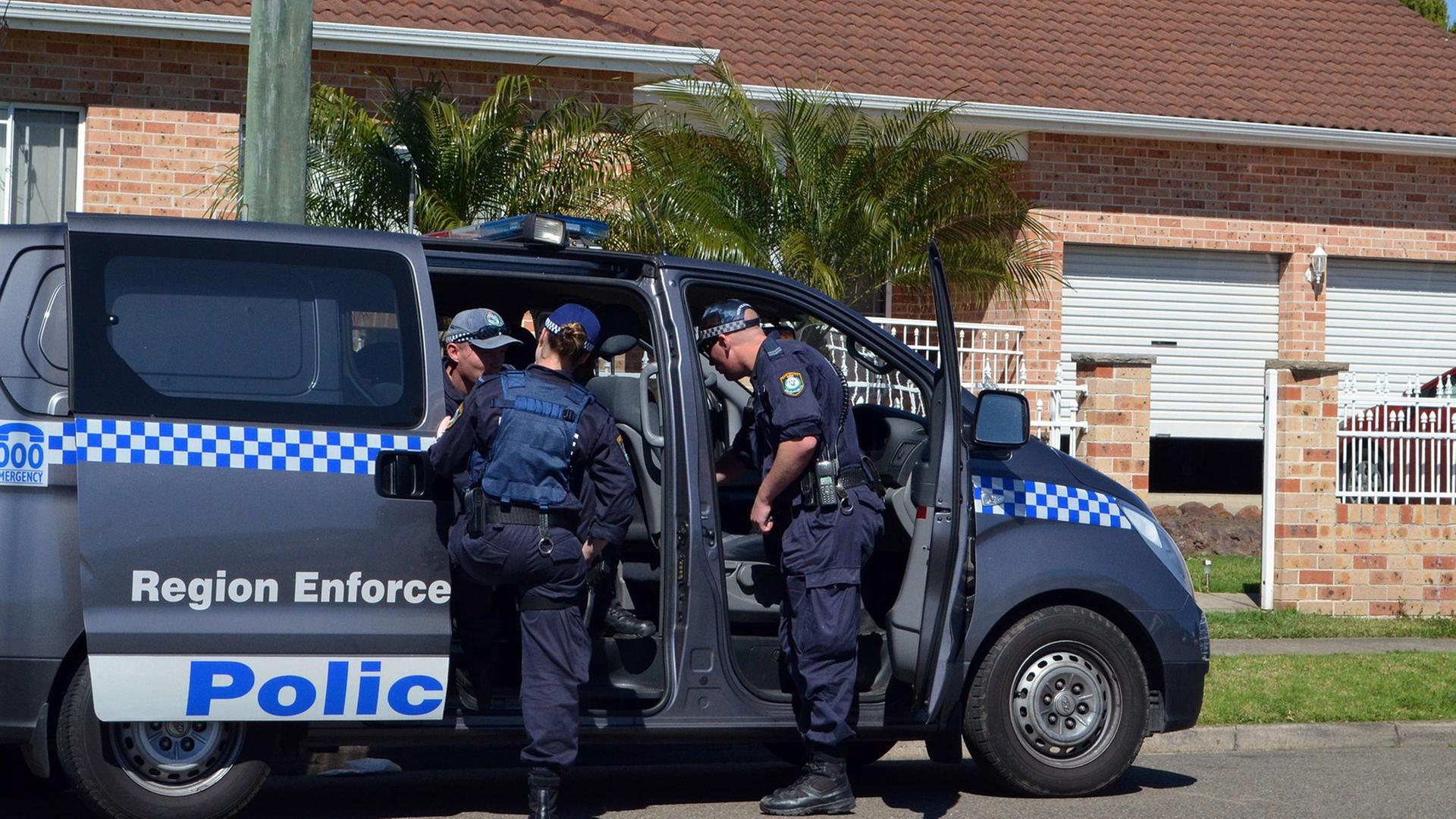 Australische Polizisten steigen in einen Mannschaftswagen vor einem Wohnhaus. Australische Polizisten steigen in einen Mannschaftswagen vor einem Wohnhaus.