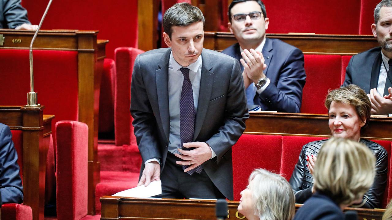 Aurélien Taché steht zwischen sitzenden Abgeordneten in der französischen Nationalversammlung Aurélien Taché steht zwischen sitzenden Abgeordneten in der französischen Nationalversammlung