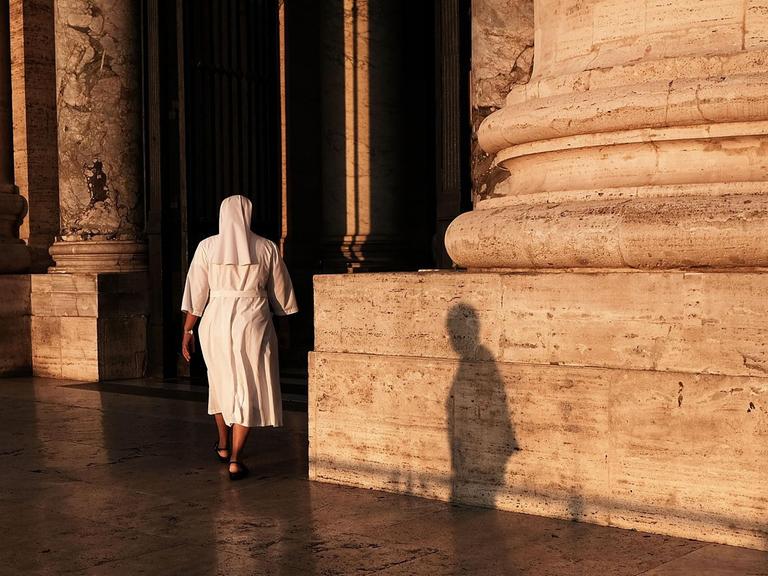 Eine Nonne betritt die St. Peter's Basilica im Vatikan in Rom in der Dämmerung.