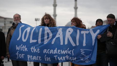 Eine Delegation von Akademikern und Menschenrechtsaktivisten aus Deutschland demonstriert vor einem Gericht in Istanbul und hält dazu ein Banner hoch, auf dem sie Solidarität mit den Angeklagten fordern..