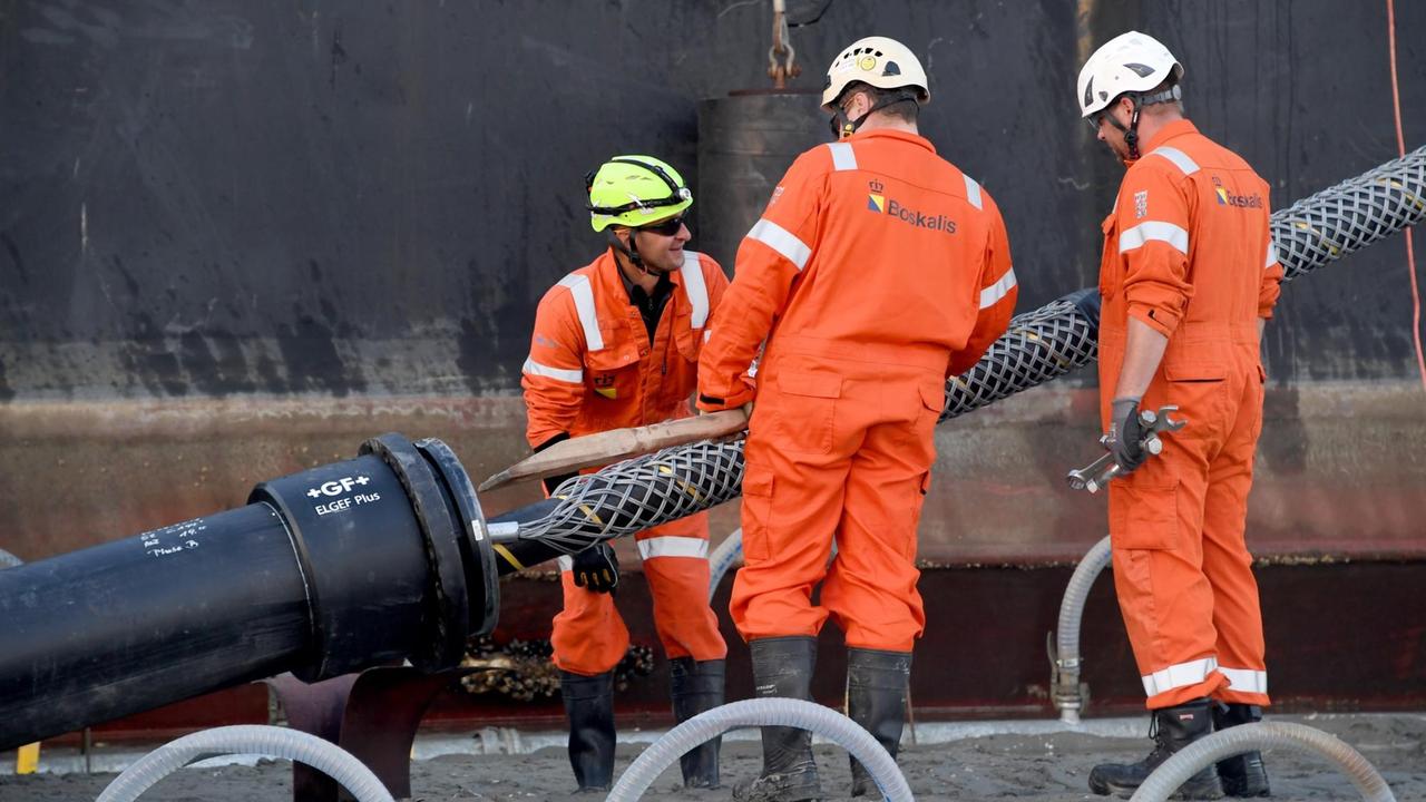 Das Endstück eines Seekabels wird von einem Kabelverlegeschiff im Watt unter dem Deich hindurch an Land gezogen. Das Endstück eines Seekabels wird von einem Kabelverlegeschiff im Watt unter dem Deich hindurch an Land gezogen.