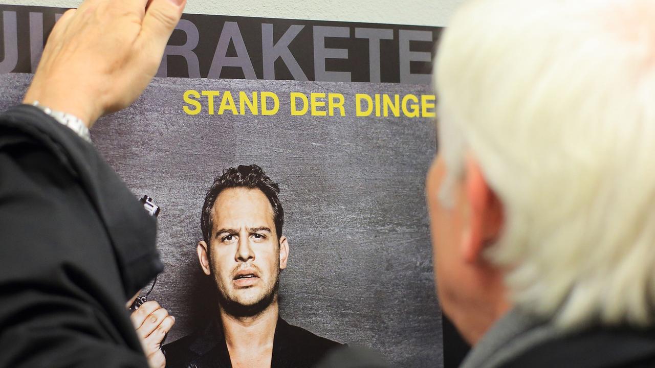 Der Fotograf Jim Rakete signiert ein Plakat mit dem Konterfei des Schauspielers Moritz Bleibtreu.