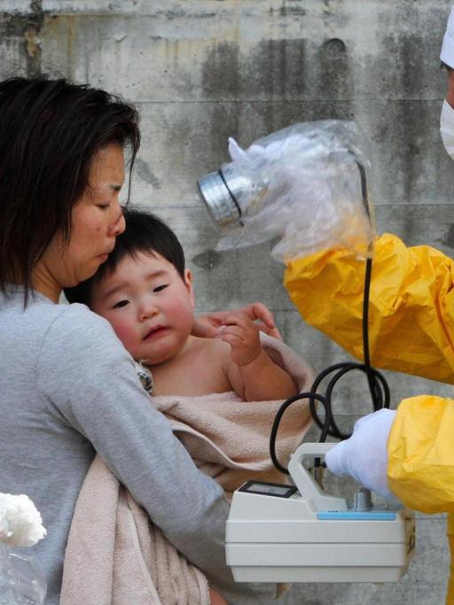 Eine Mutter und ihr Kind werden nach dem Atomunfall von Fukushima im März 2011 auf radioaktive Strahlung untersucht.