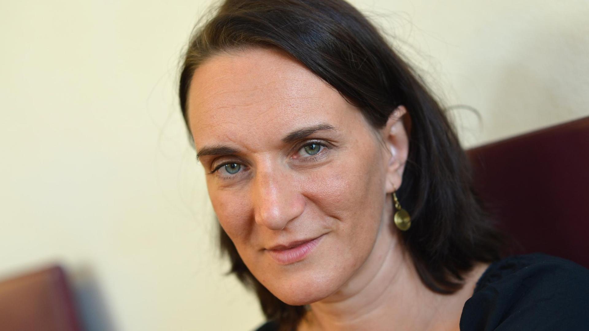 Die Autorin Terezia Mora blickt am Rande der Verleihung des Deutschen Buchpreises 2013 in die Kamera. Sie hat ein schwarzes Shirt an und schulterlange braune Haare. Sie trägt einen goldenen oder messingsfarbenen Ohrhänger. Die Autorin Terezia Mora blickt am Rande der Verleihung des Deutschen Buchpreises 2013 in die Kamera. Sie hat ein schwarzes Shirt an und schulterlange braune Haare. Sie trägt einen goldenen oder messingsfarbenen Ohrhänger.