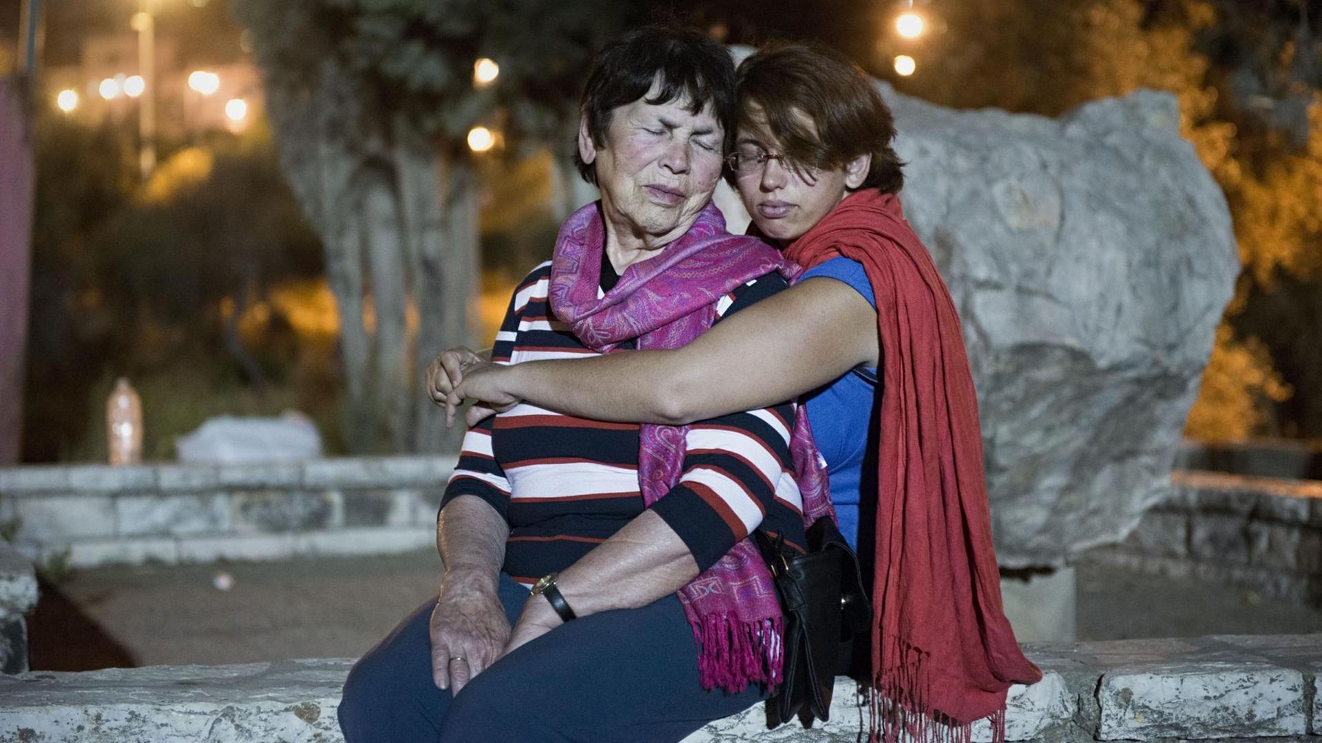 Holocaustueberlebende Pnina Katzir wird von ihrer Enkelin Yael im Sitzen umarmt, beide haben die Augen geschlossen. Jerusalem