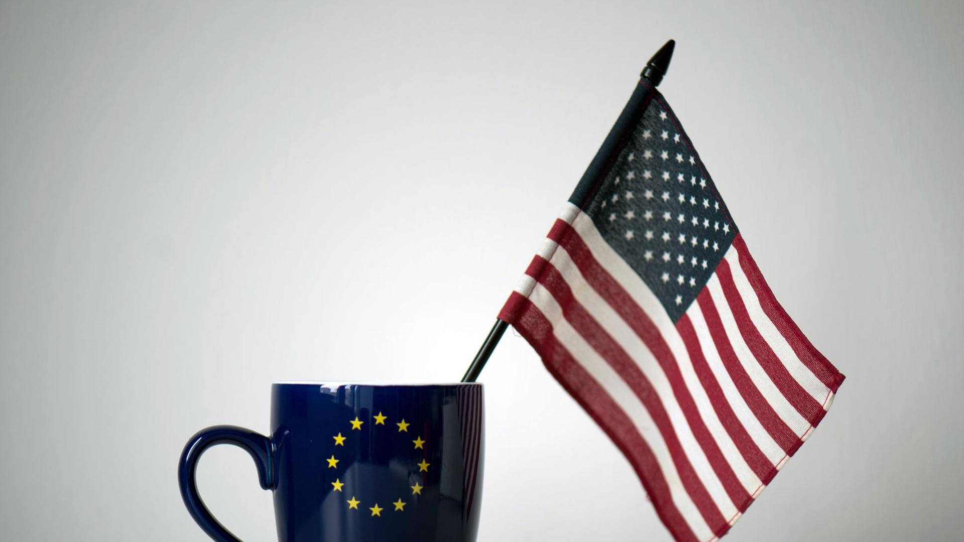 In einer Tasse mit einem EU-Symbol steckt eine US-Fahne, aufgenommen in einem Büro in Dresden. In einer Tasse mit einem EU-Symbol steckt eine US-Fahne, aufgenommen in einem Büro in Dresden.