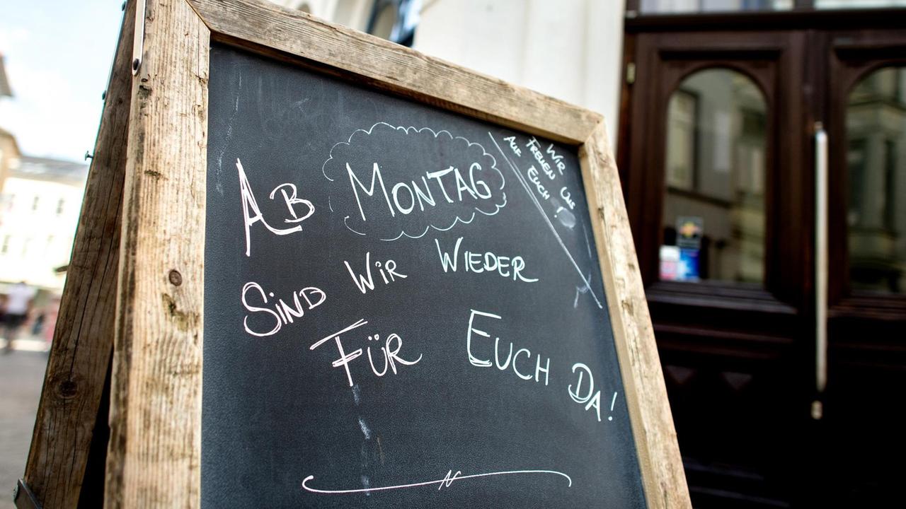 Ein Schild mit der Aufschrift "Ab Montag sind wir wieder für euch da!" steht in der Innenstadt von Oldenburg vor einem Café.