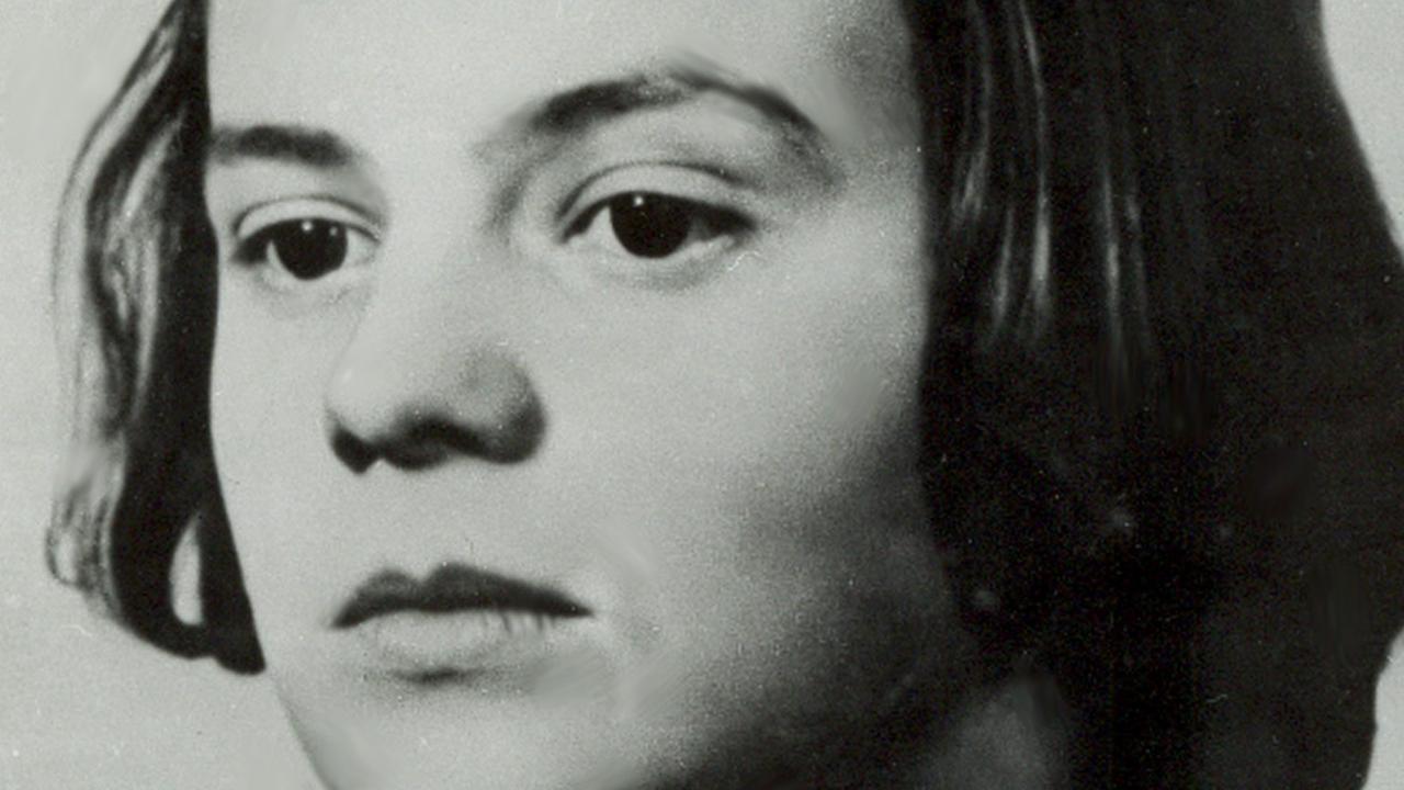 Ein Schwarzweiß-Foto zeigt eine vielleicht 15-jährige Frau mit ernsten Blick in die Kamera schauend Ein Schwarzweiß-Foto zeigt eine vielleicht 15-jährige Frau mit ernsten Blick in die Kamera schauend