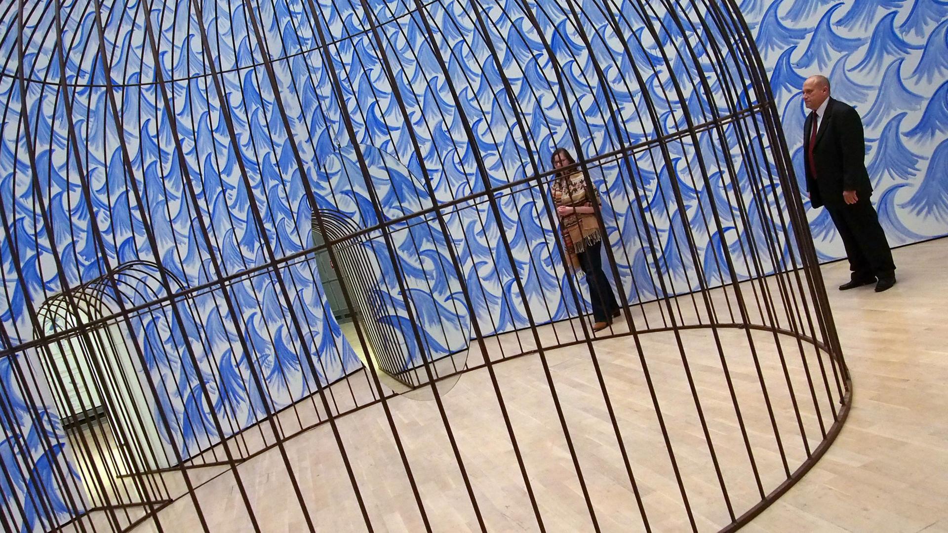 Eine Besucherin und ein Museumsmitarbeiter stehen am 11.11.2015 in der Kunstausstellung "Jeppe Hein. This Way" im Kunstmuseum Wolfsburg vor einem riesigen Käfig, in dem ein Spiegel kreist. Eine Besucherin und ein Museumsmitarbeiter stehen am 11.11.2015 in der Kunstausstellung "Jeppe Hein. This Way" im Kunstmuseum Wolfsburg vor einem riesigen Käfig, in dem ein Spiegel kreist.