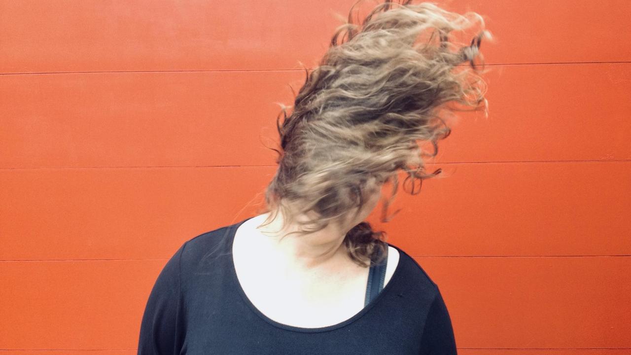 Anna Mateur sitzt auf einem Stuhl ihre Haarmähne wirbelt vor ihrem Gesicht, das man nchct sieht Anna Mateur sitzt auf einem Stuhl ihre Haarmähne wirbelt vor ihrem Gesicht, das man nchct sieht