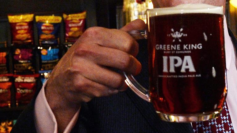 Eine Hand hält ein Bier in einem englischen Pub Eine Hand hält ein Bier in einem englischen Pub