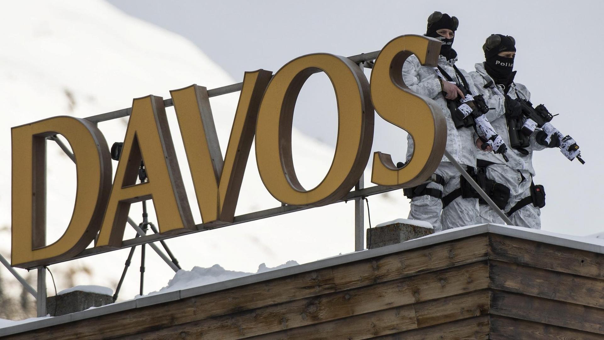 Vermummte Beamte der Schweizer Polizei in Wintermontur und Waffen stehen auf dem Dach des Kongresshotels in Davos. Vermummte Beamte der Schweizer Polizei in Wintermontur und Waffen stehen auf dem Dach des Kongresshotels in Davos.