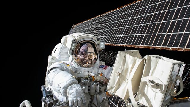 Astronaut im Weltall arbeitet an einer Raumstation.