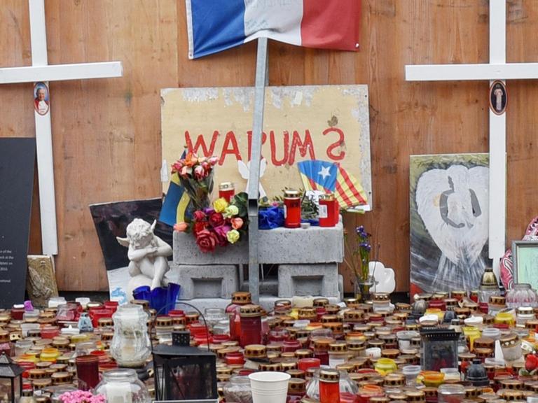 Kerzen und Kreuze stehen vor der Gedenkstelle für die Opfer des Anschlags auf dem Breitscheidplatz in Berlin. Unter dem Schriftzug "Warum" ist auch eine Fahne Kataloniens als Beileidsbekundung für den Terroranschlag in Barcelona zu sehen.