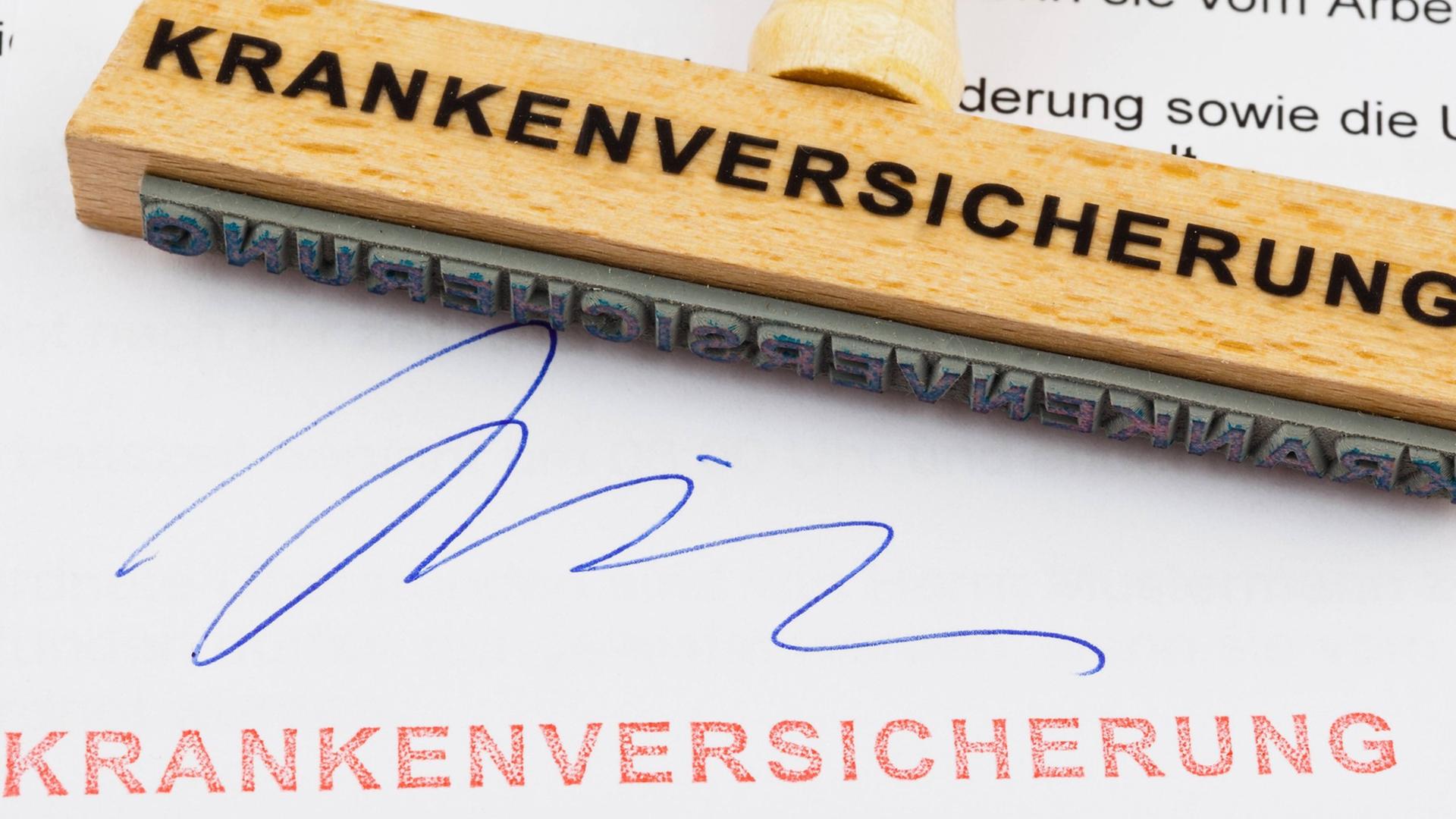 Unterschrift und Stempel "Krankenversicherung" auf einem Blatt Papier, auf dem der Stempel mit der Aufschrift "Krankenversicherung" liegt Unterschrift und Stempel "Krankenversicherung" auf einem Blatt Papier, auf dem der Stempel mit der Aufschrift "Krankenversicherung" liegt