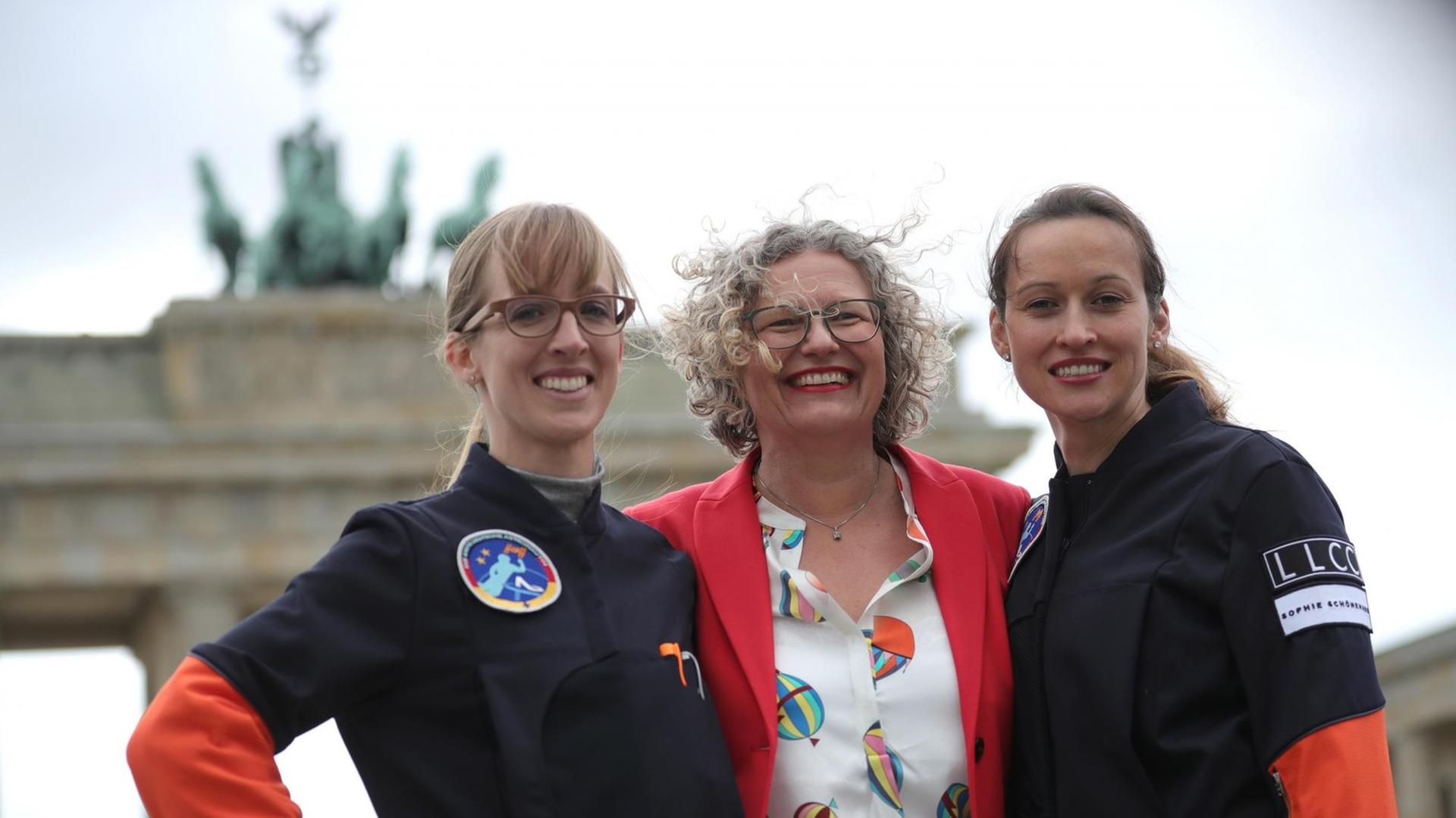 Das Foto zeigt Insa Thiele-Eich und Nicola Baumann, die auf einen Flug ins All zur ISS vorbereitet werden. Zusammen mit der Diplom-Ingenieurin Claudia Kessler stehen sie vor dem Brandenburger Tor. Das Foto zeigt Insa Thiele-Eich und Nicola Baumann, die auf einen Flug ins All zur ISS vorbereitet werden. Zusammen mit der Diplom-Ingenieurin Claudia Kessler stehen sie vor dem Brandenburger Tor.