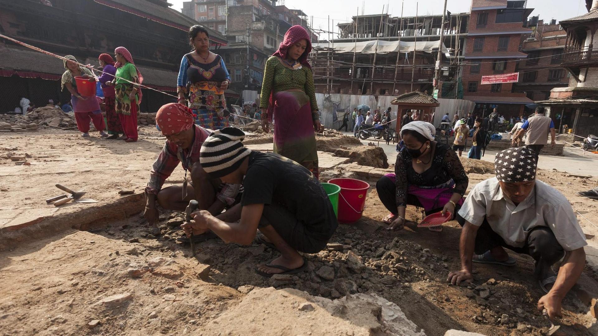 Man sieht Arbeiter in Kathmandu, die auf dem Gelände des eingestürzten Kastamandap Tempels beschäftigt sind.