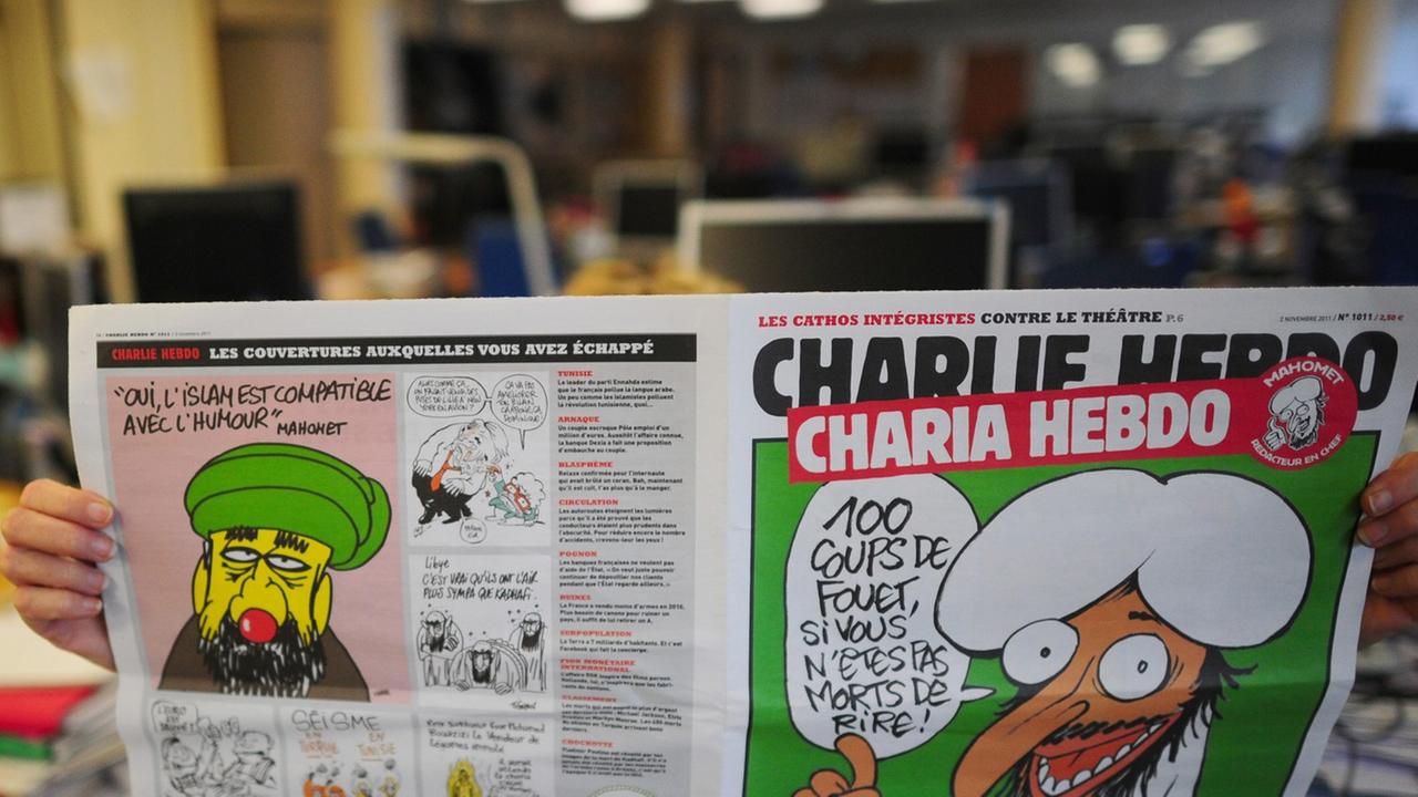 Jemand liest eine ältere Ausgabe von "Charlie Hebdo" mit einer Mohammed-Karikatur auf dem Titel. Jemand liest eine ältere Ausgabe von "Charlie Hebdo" mit einer Mohammed-Karikatur auf dem Titel.