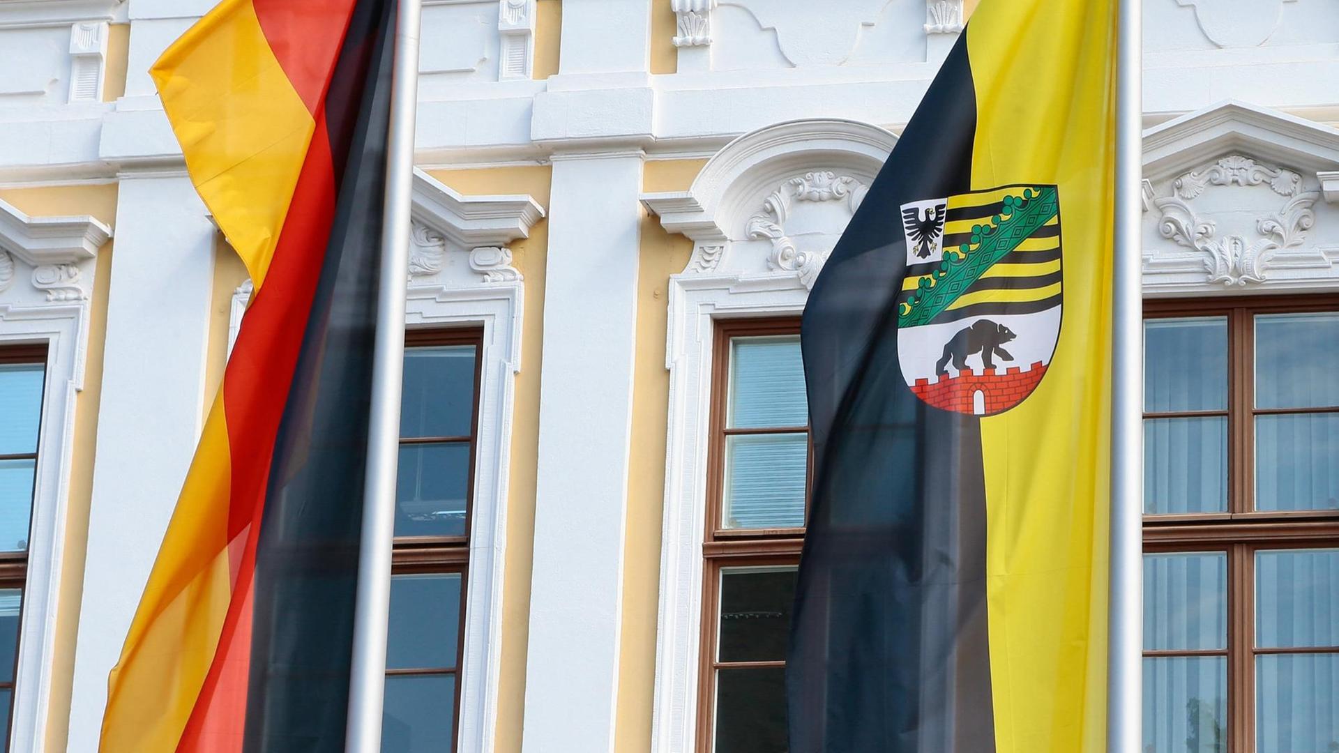 Deutschland- und Landesfahne von Sachsen-Anhalt vor der gelb-weißen Fassades des Landtags von Sachsen-Anhalt am Domplatz in Magdeburg. Deutschland- und Landesfahne von Sachsen-Anhalt vor der gelb-weißen Fassades des Landtags von Sachsen-Anhalt am Domplatz in Magdeburg.