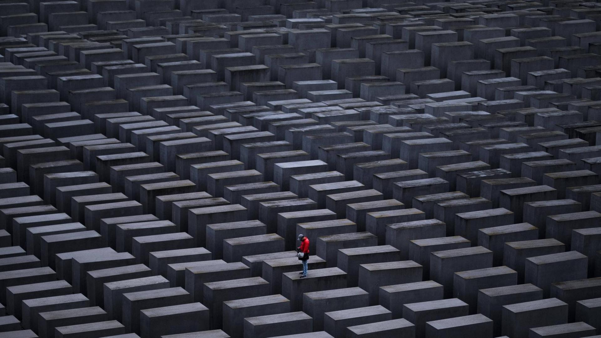 Ein Mann mit roter Jacke steht auf einer Stele am Holocaust-Mahnmal in Berlin