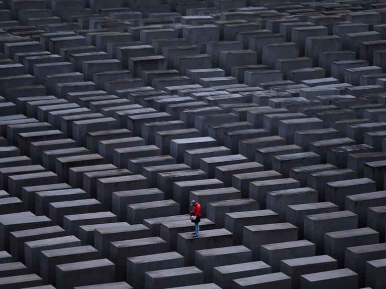 Ein Mann mit roter Jacke steht auf einer Stele am Holocaust-Mahnmal in Berlin