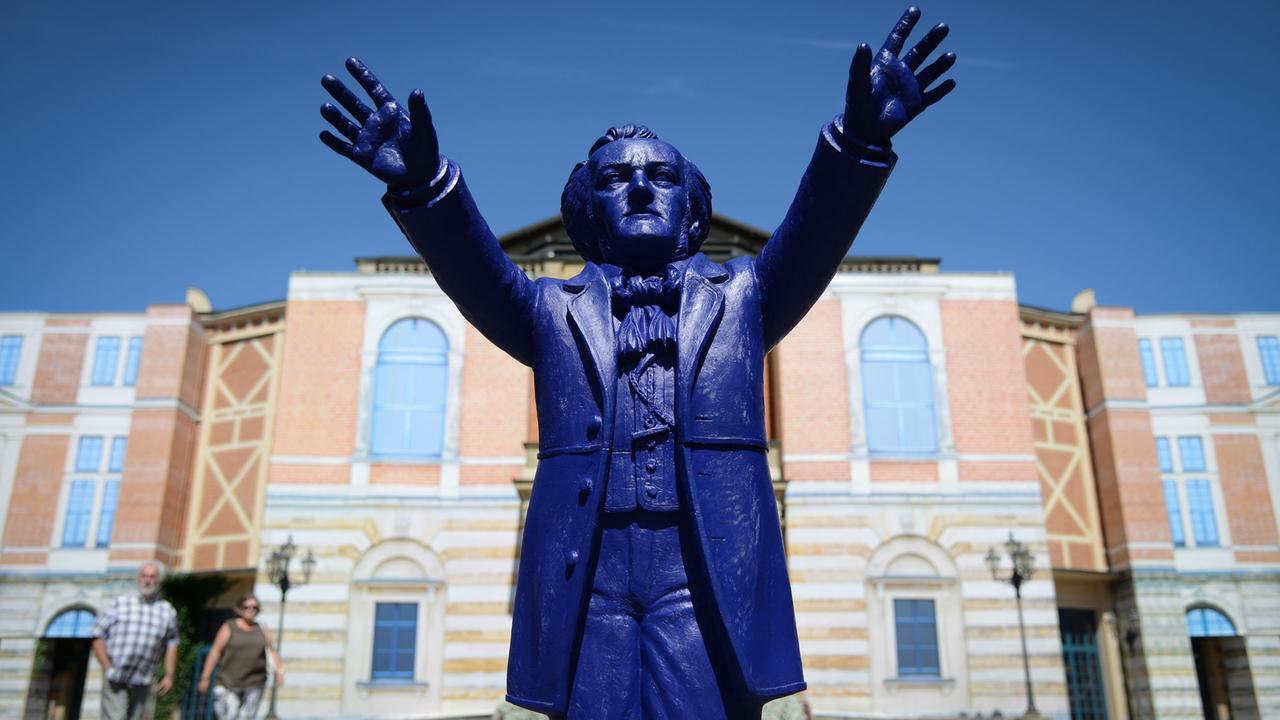Ein Plastik-Wagner des Künstlers Ottmar Hörl "dirigiert" vor dem Königsportal des Festspielhauses auf dem Grünen Hügel in Bayreuth (Bayern). Ein Plastik-Wagner des Künstlers Ottmar Hörl "dirigiert" vor dem Königsportal des Festspielhauses auf dem Grünen Hügel in Bayreuth (Bayern).