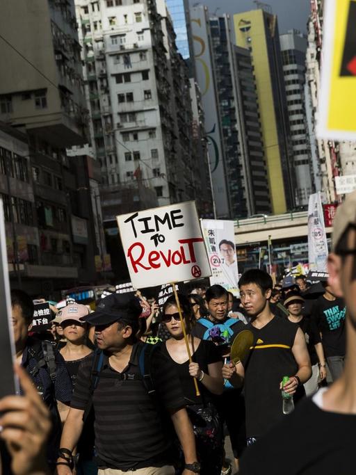 Demonstranten halten Schilder mit chinesischen Schriftzeichen hoch.