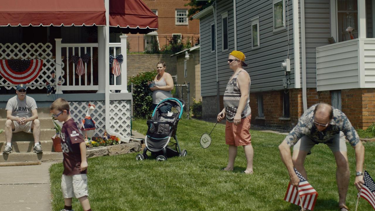 Vor einem Haus in den USA stehen und sitzen mehrere Menschen. Vor einem Haus in den USA stehen und sitzen mehrere Menschen.