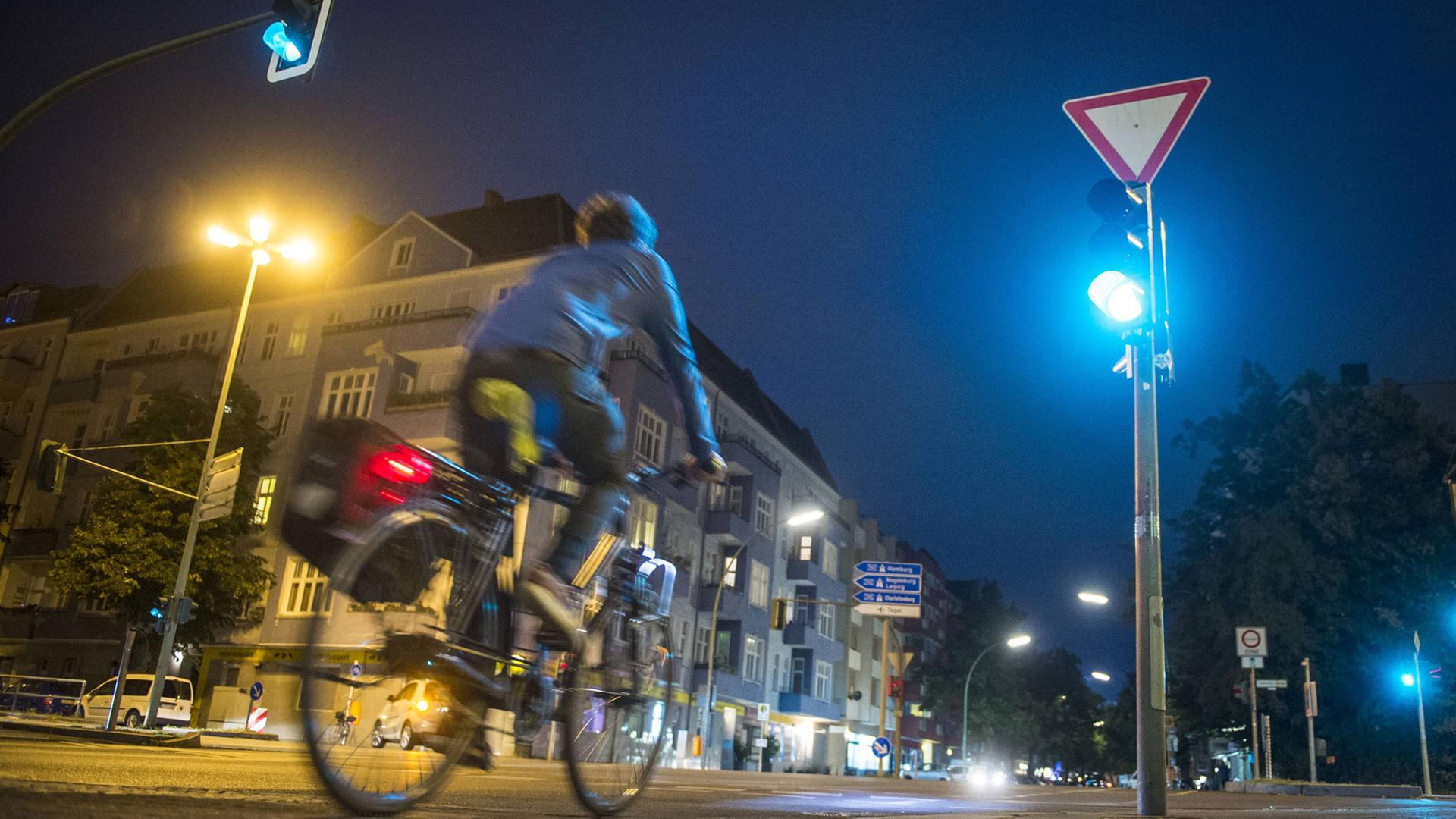 Ein Radfahrer fährt nachts über eine grüne Kreuzung. Ein Radfahrer fährt nachts über eine grüne Kreuzung.