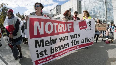 "Notruf: Mehr von uns ist besser für alle!" steht bei einer Demonstration von streikendem Pflegepersonal an der Berliner Charite - Campus Virchow Klinikum auf einem Transparent.