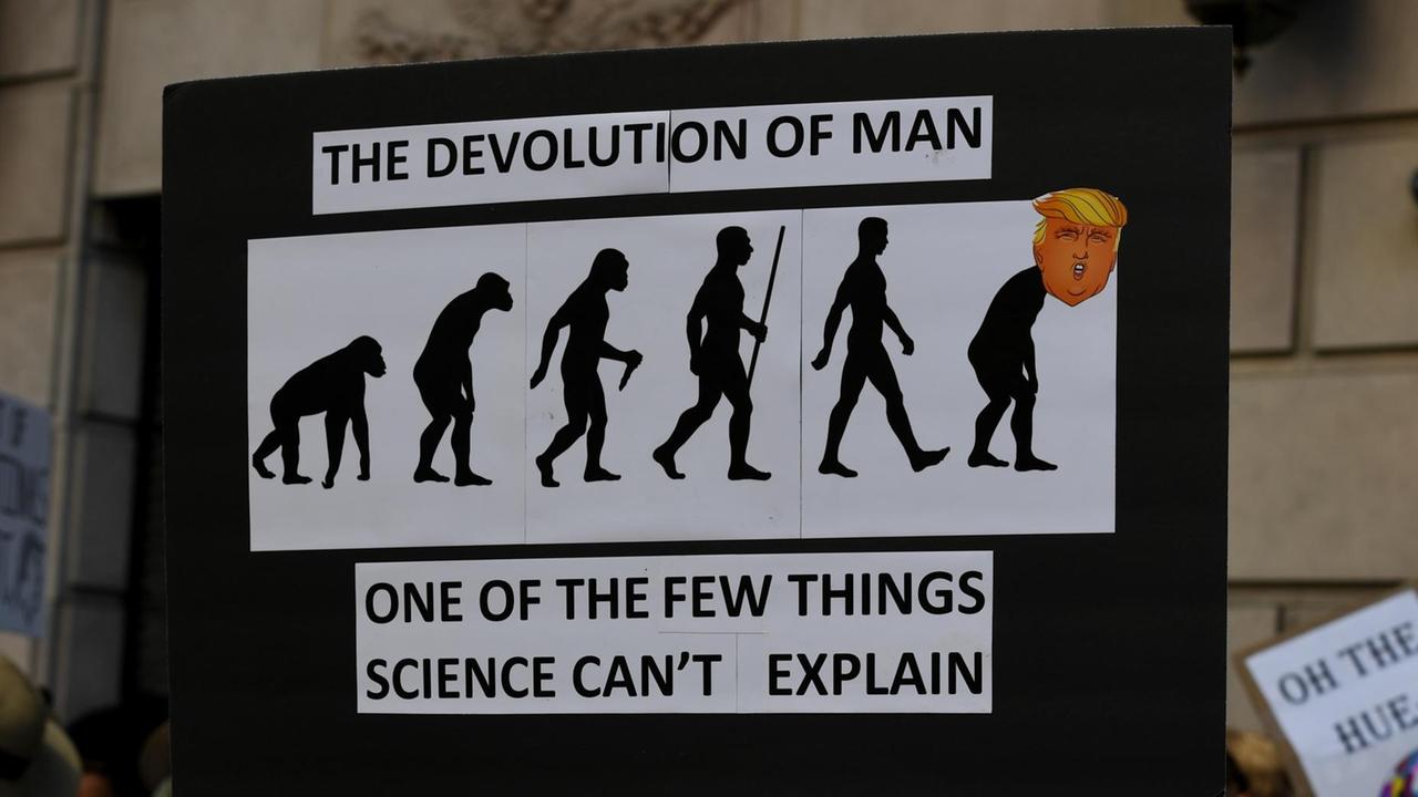 Ein Schild auf dem "March for Science", dem Marsch für die Wissenschaft im April 2017, auf dem bildlich die Entwicklung des Menschen zu sehen ist, auf die letzte Figur ist der Kopf von Präsident Trump montiert. Ein Schild auf dem "March for Science", dem Marsch für die Wissenschaft im April 2017, auf dem bildlich die Entwicklung des Menschen zu sehen ist, auf die letzte Figur ist der Kopf von Präsident Trump montiert.