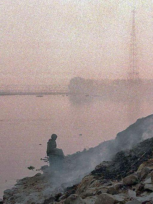 Zwei Männern und ein Elefant sind in der dunstigen Luft neben einem brennender Müllhalde am Yamuna Fluß in Neu Delhi nur als Umriss zu erkennen. Der heilige Yamuna Fluß ist stark durch industrielle Abwässer verschmutzt.
