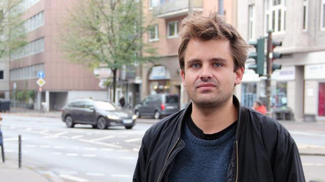 Der Regisseur und Dramaturg Julian Pörksen steht an einer Straße in Köln