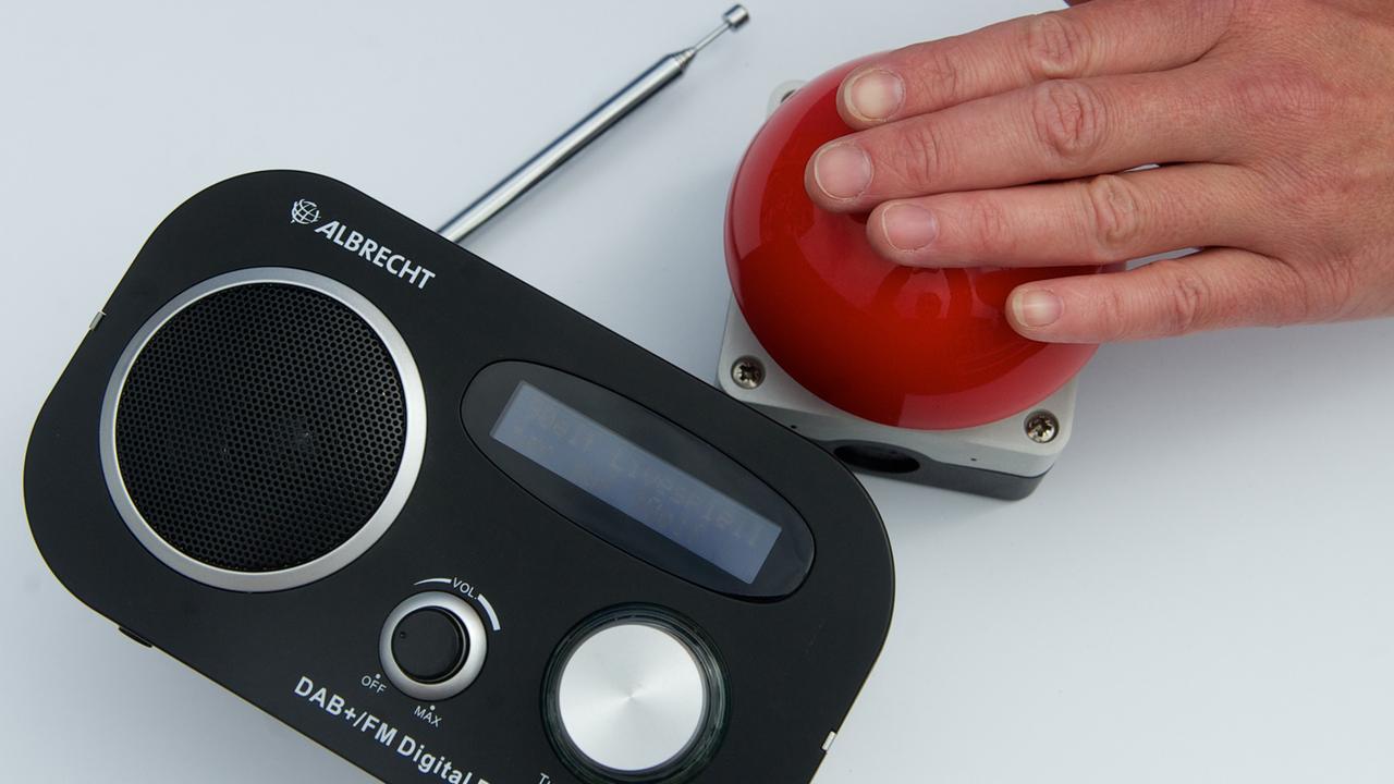 Ein Digitalradioempfänger liegt neben einem Startknopf. Ein Digitalradioempfänger liegt neben einem Startknopf.