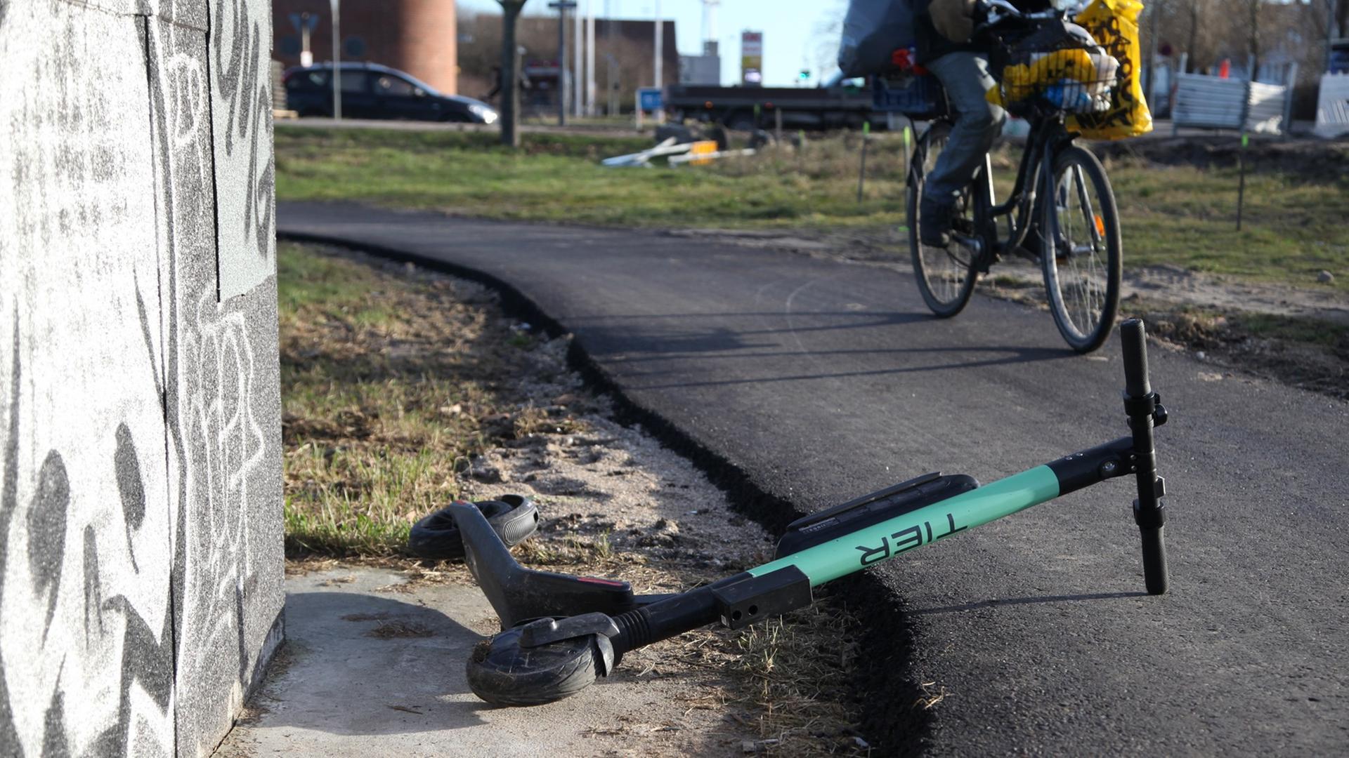 Ein Radfahrer weicht auf einem Radweg in Kopenhagen einem umgekippten E-Scooter aus. Ein Radfahrer weicht auf einem Radweg in Kopenhagen einem umgekippten E-Scooter aus.