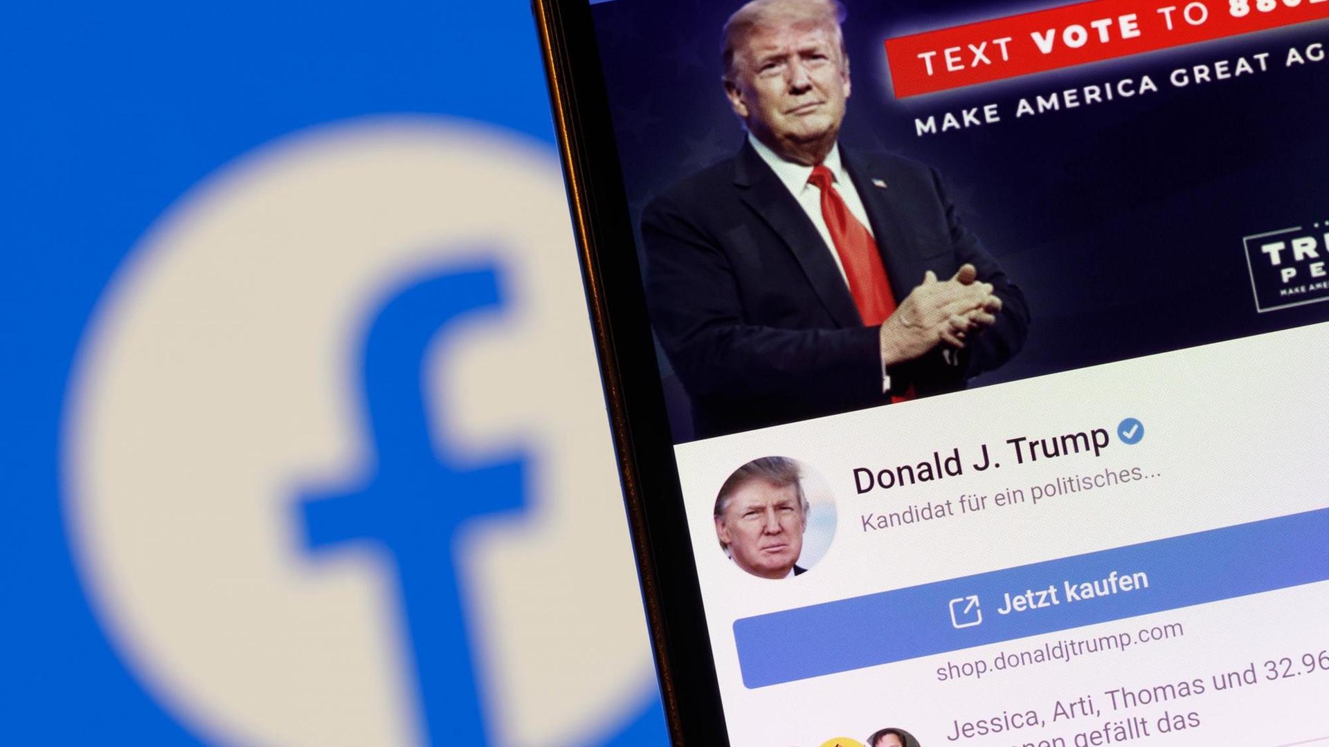 Der Facebook-Account von US-Präsident Donald J. Trump auf einem Handy vor einem Bildschirm mit einem Facebook-Logo. Der Facebook-Account von US-Präsident Donald J. Trump auf einem Handy vor einem Bildschirm mit einem Facebook-Logo.