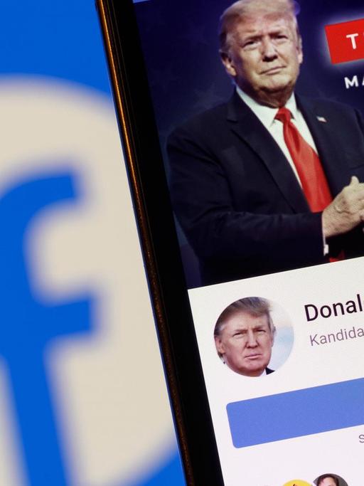 Der Facebook-Account von US-Präsident Donald J. Trump auf einem Handy vor einem Bildschirm mit einem Facebook-Logo.