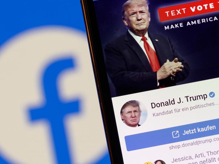 Der Facebook-Account von US-Präsident Donald J. Trump auf einem Handy vor einem Bildschirm mit einem Facebook-Logo.