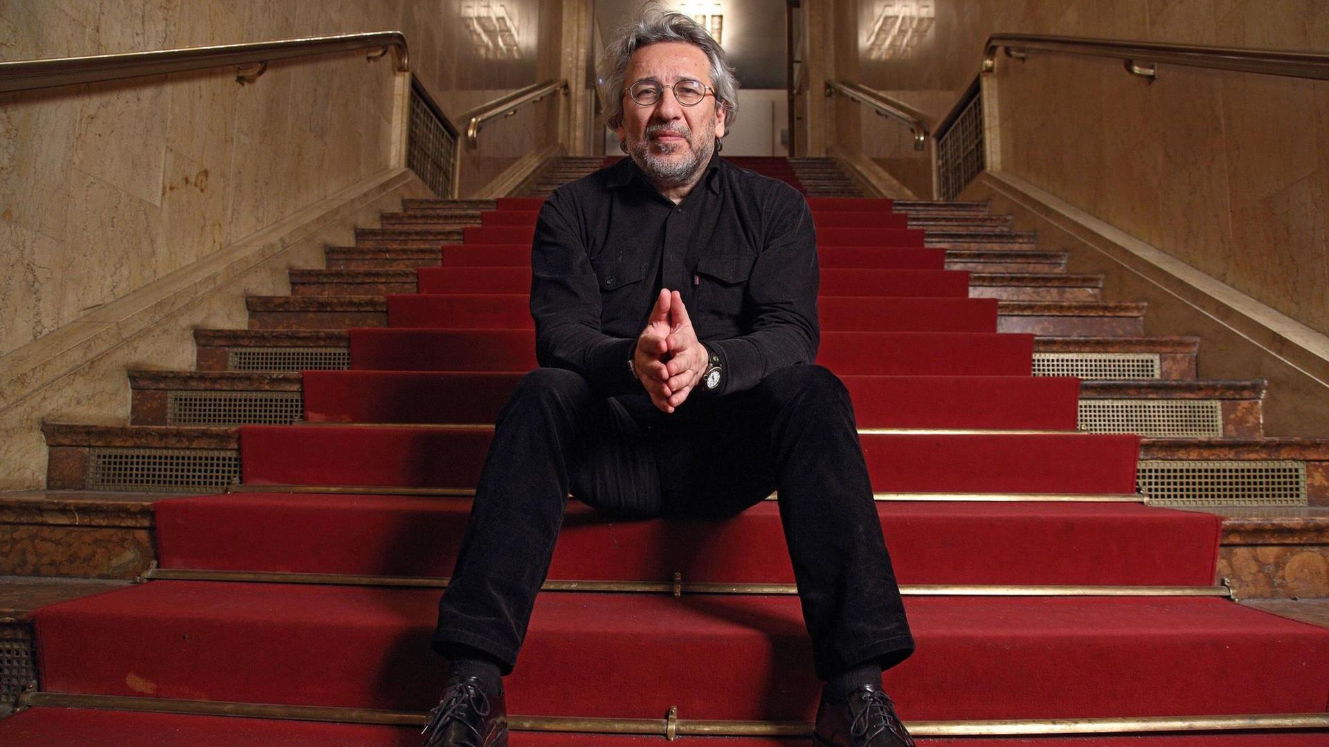 Can Dündar im Maxim Gorki Theater auf einer roten Treppe.