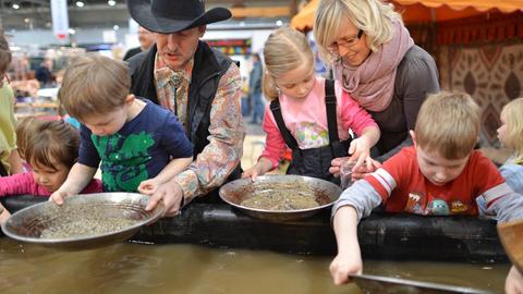 Kinder versuchen sich auf einer Messe in Leipzig im Goldwaschen.