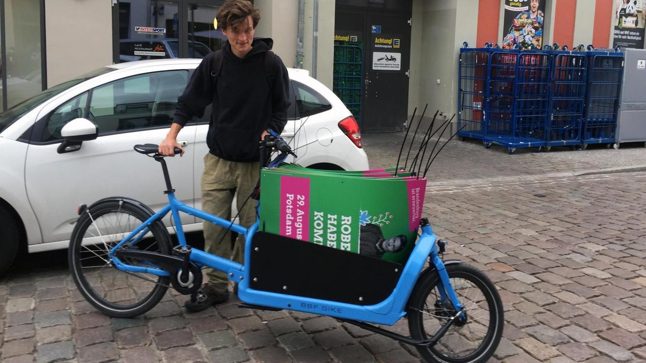 Robert Funke, Sprecher der Grünen Jugend Brandenburg, mit einem Lastenfahrrad, auf dem Wahlplakate transportiert werden.
